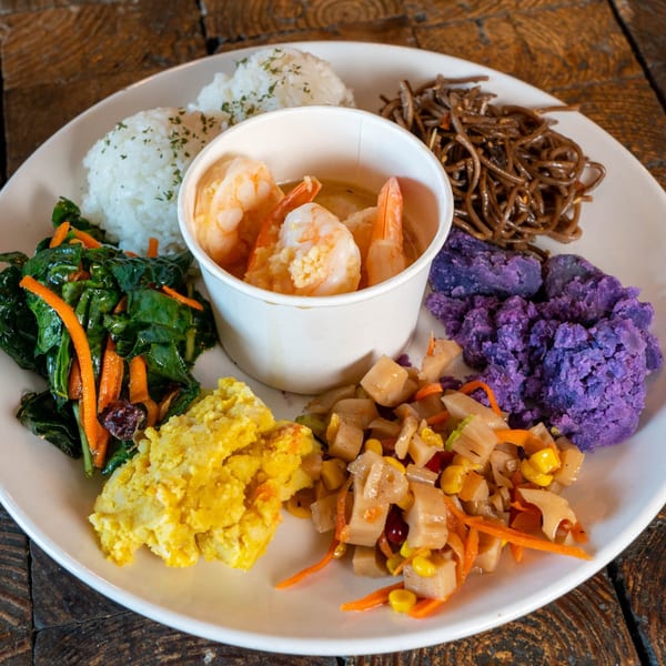 A Kaimana Farm Cafe plate with shrimp, rice, noodles, purple sweet potato, scrambled eggs, and vegetables.