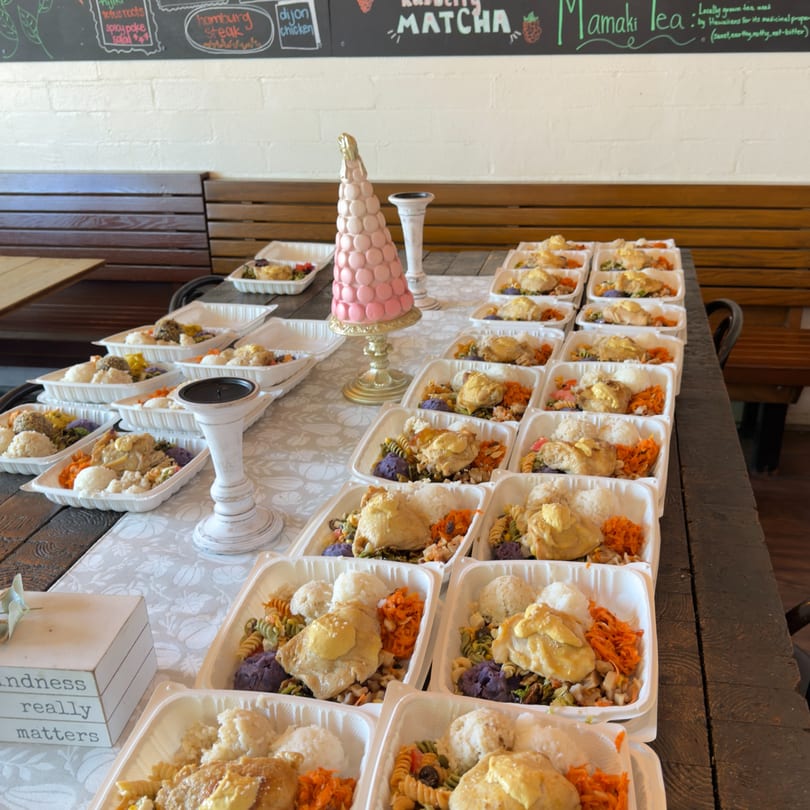 Rows of Kaimana Farm Cafe's healthy takeout meals with chicken, rice, and vegetables on a long table.