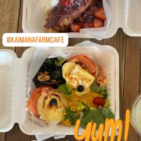 Two takeout containers with Kaimana Farm Cafe's healthy meals, including French toast and eggs Benedict.