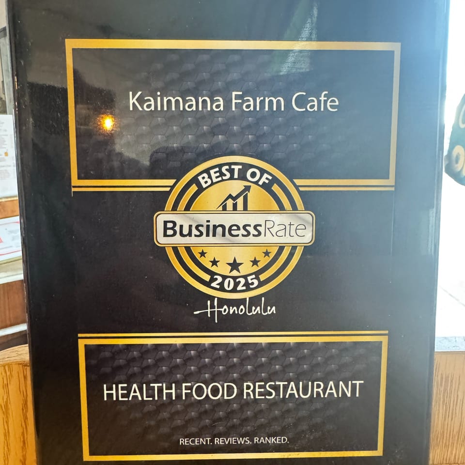 Kaimana Farm Cafe's "Best of BusinessRate 2025 Honolulu Health Food Restaurant" award plaque.