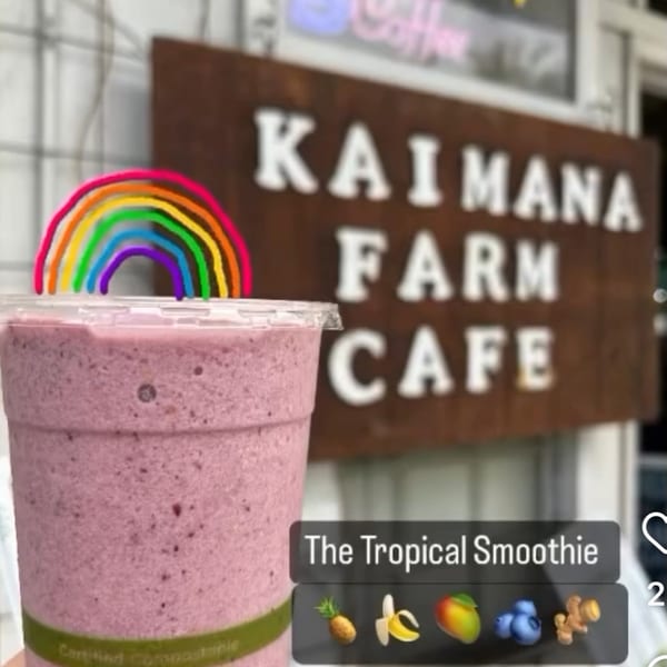A Kaimana Farm Cafe Tropical Smoothie with a rainbow straw, pineapple, banana, mango, blueberry, and ginger.