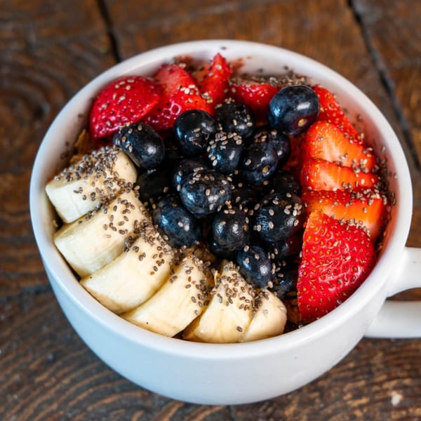 A healthy Kaimana Farm Cafe acai bowl with bananas, blueberries, strawberries, and chia seeds.